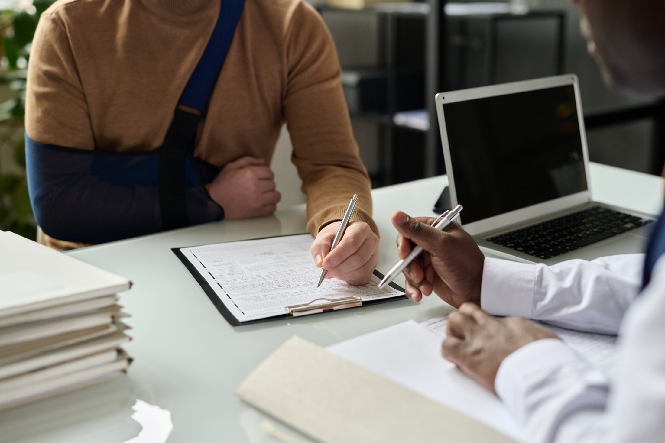 Pessoa com braço imobilizado preenchendo documentos